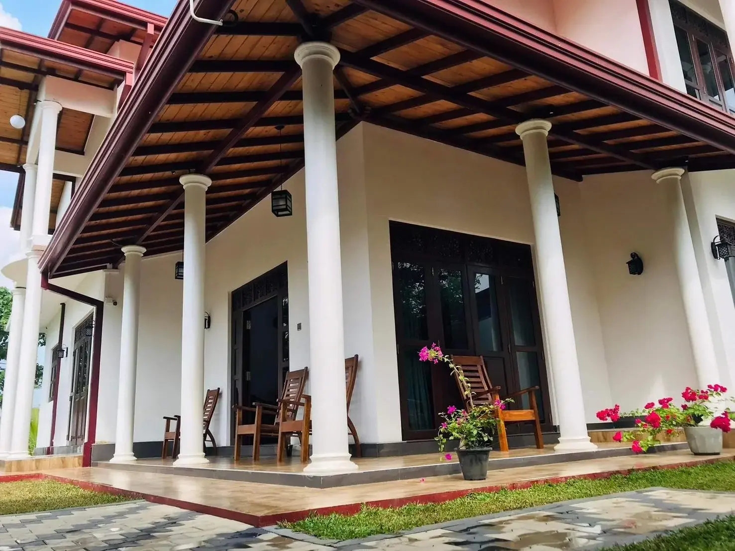 The homestay veranda with wooden chairs and flowering plants